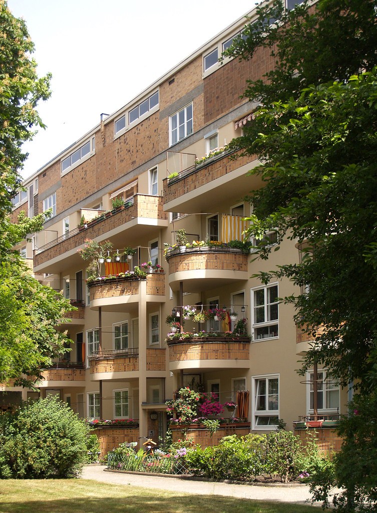 Apartment building courtyard with stacked balconies and greenery.